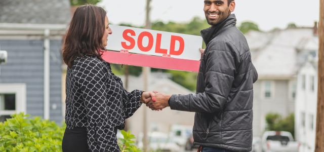 Image of two people holding up a "sold" sign